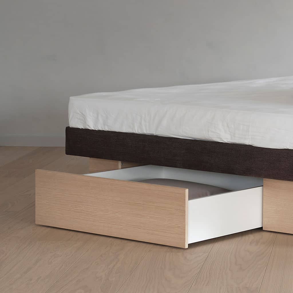 Un lit à eau vu de face, sans tête de lit : le socle en chêne clair, le bandeau sombre du cadre au-dessus, puis le couchage.