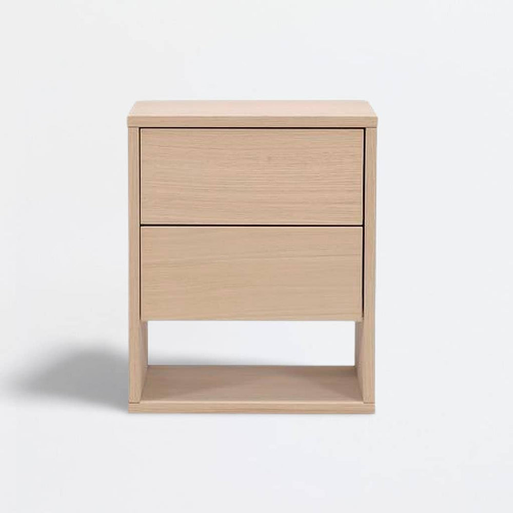 Table de chevet Akva posée au sol, deux tiroirs à poussoir et niche ouverte, vue de trois quarts