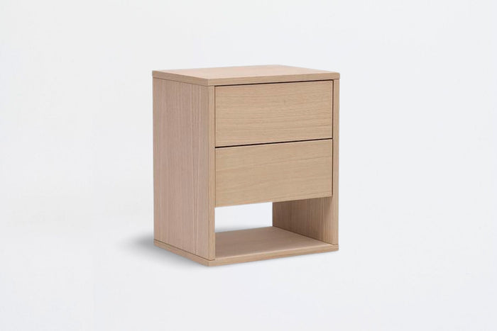 Table de chevet Akva posée au sol, deux tiroirs à poussoir et niche ouverte, sur fond neutre