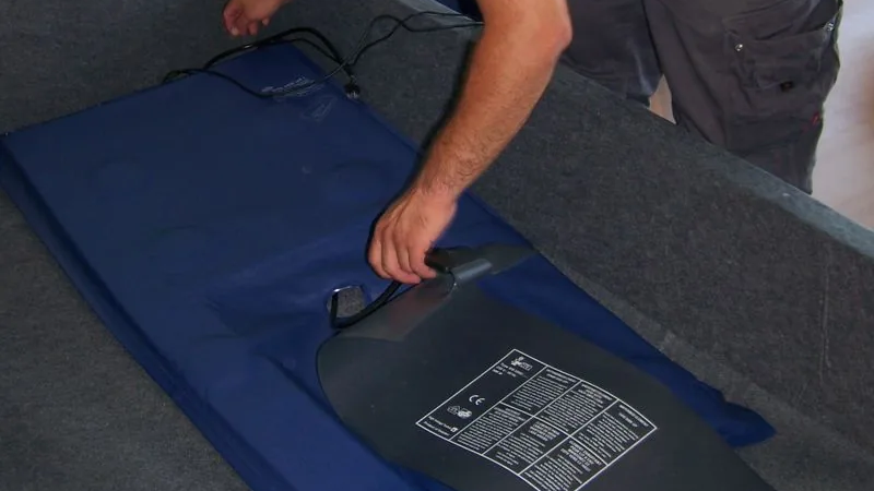 Un technicien met en place la plaque chauffante Akva à plat dans le cadre du lit