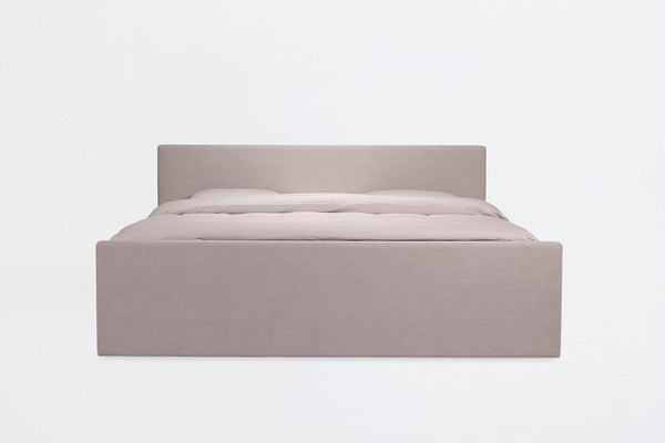 Lit à eau Akva Lyra vu de face : cadre enveloppant tapissé beige clair et tête de lit basse assortie