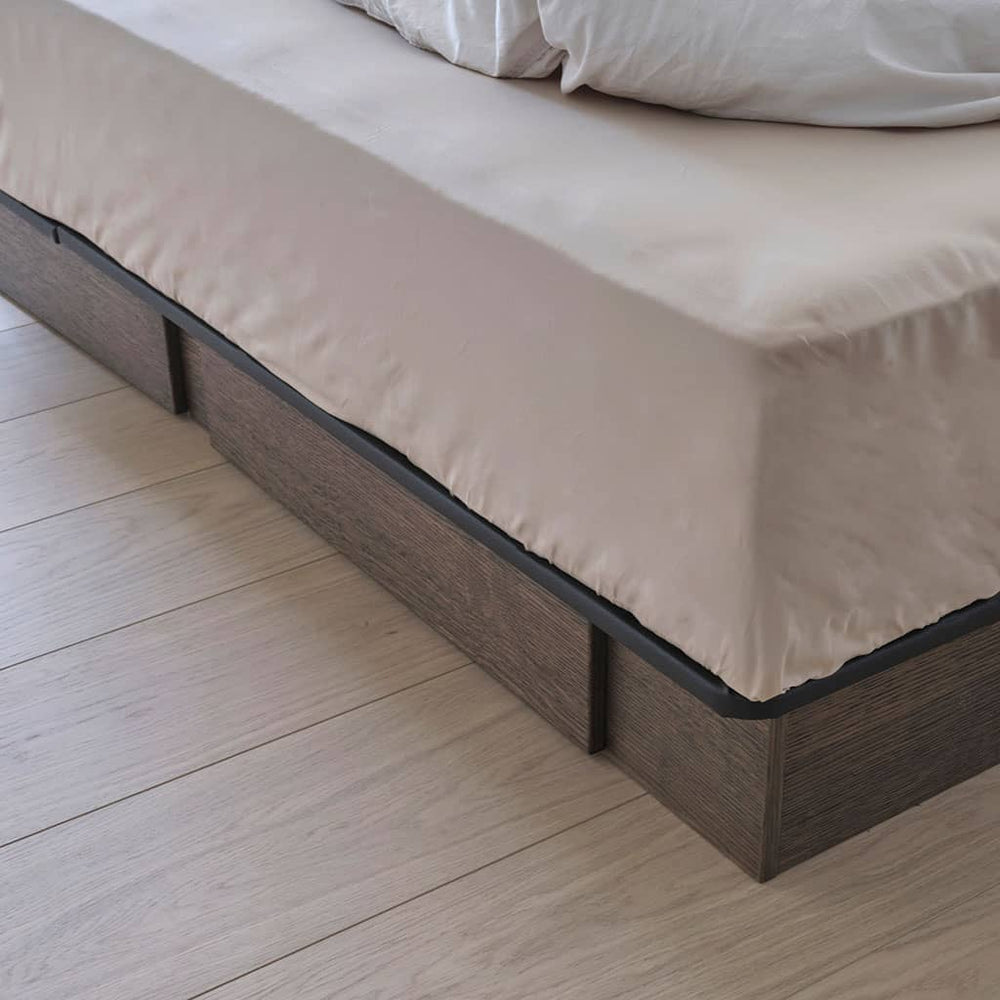 Socle en bois foncé d'un lit à eau Akva Soft, vu au ras du parquet