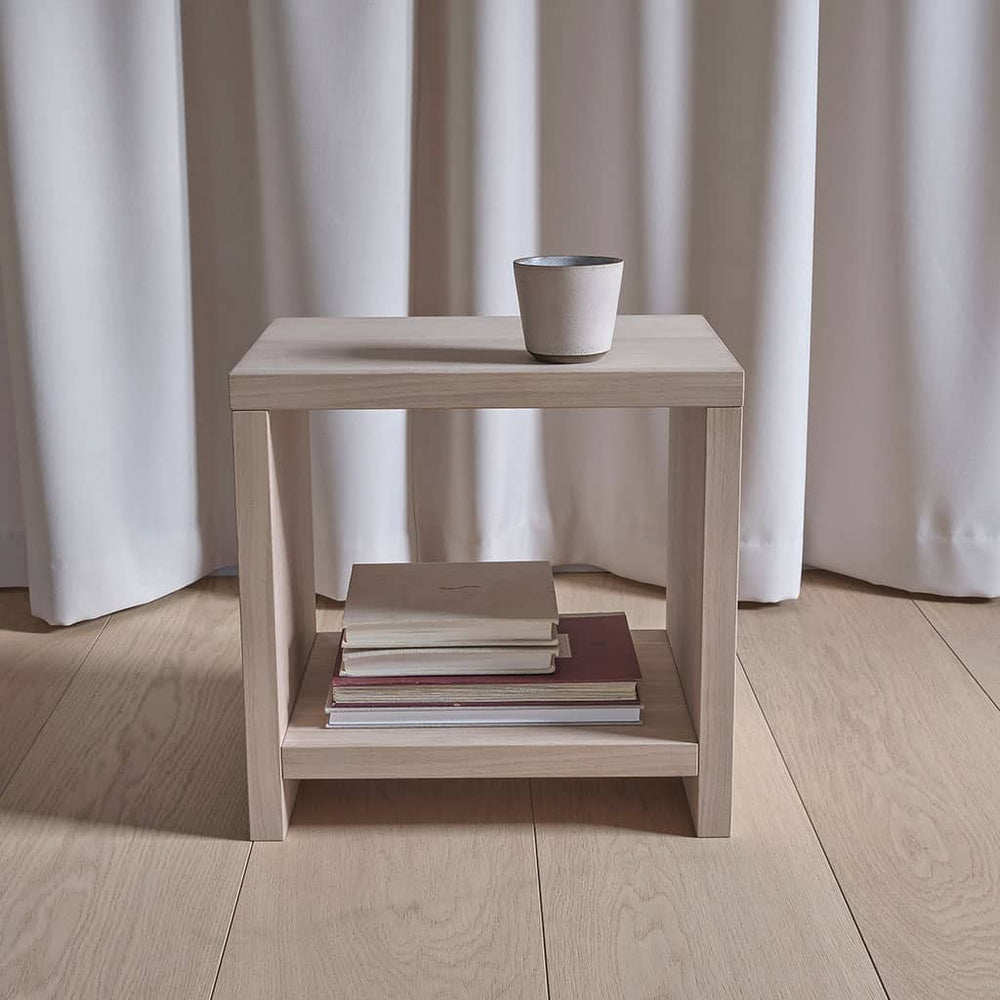 Table de chevet cube Akva de face : plateau, niche ouverte et tablette basse chargée de livres
