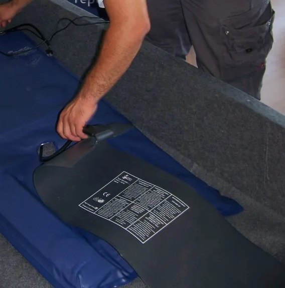 La plaque chauffante Akva posée sous le matelas, son étiquette CE visible