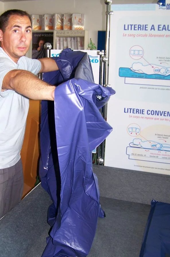 Un technicien déplie le liner de sécurité : une cuve de vinyle bleu d'un seul tenant