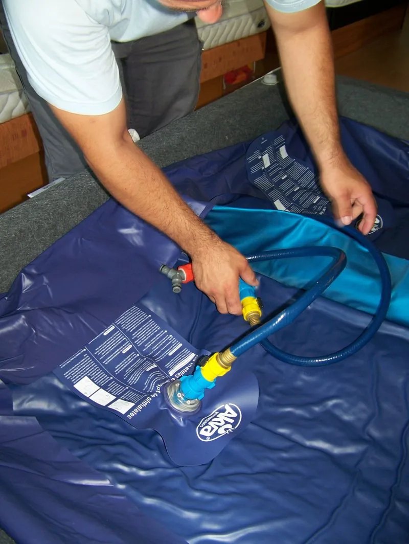 Un technicien raccorde le tuyau de remplissage à la valve du matelas