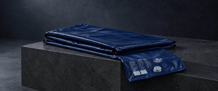 Matelas à eau Akva vide, plié sur un socle de pierre, étiquette et valve visibles