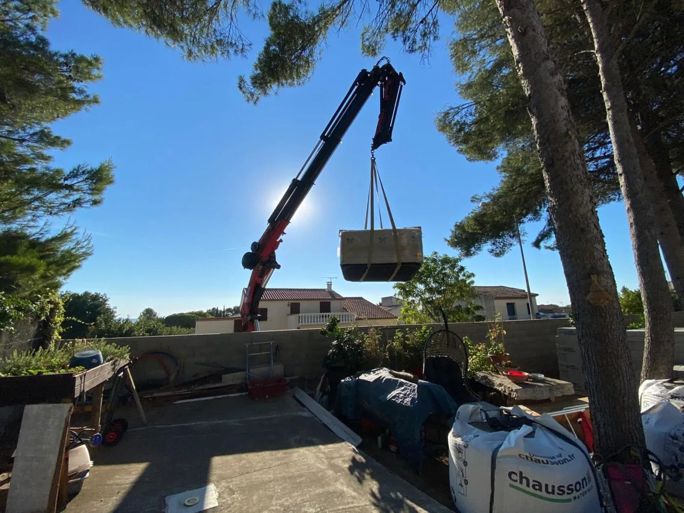 Une grue dépose un spa par-dessus une maison, sur un chantier de l'Hérault.